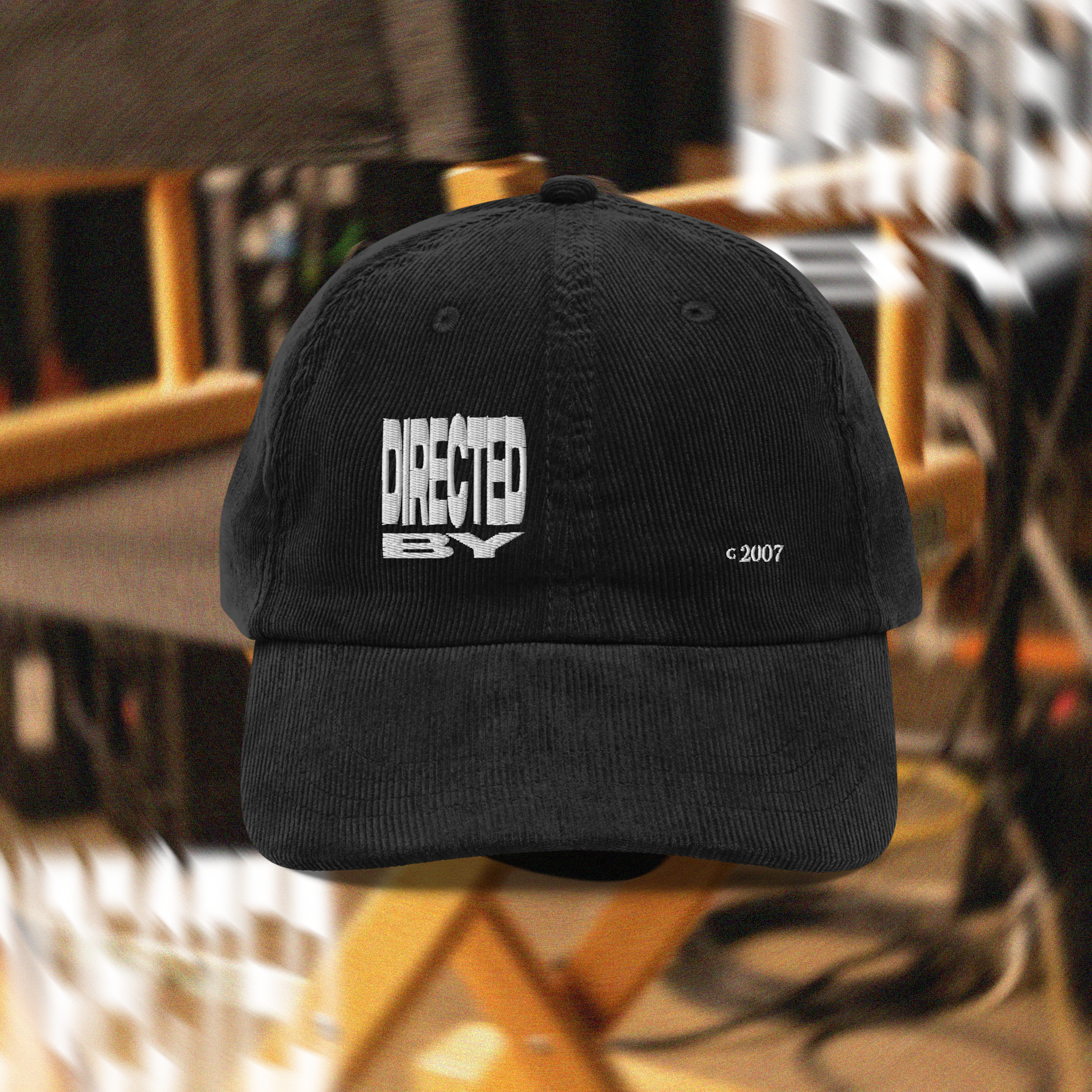 Black cap with white text that reads: "DIECTED BY" on a blurred background